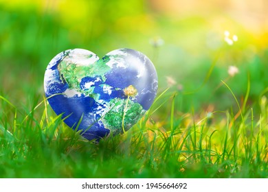 Erde in Herzform auf grünem Gras und Blumen im Sonnenlicht, Love and Save the World for the Next Generation Konzept, Earth Day Concept, Elemente dieses Bildes, bereitgestellt von der NASA
