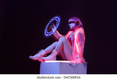 Hermosa mujer con cabello púrpura en traje futurista sobre fondo oscuro. Chica con gafas de realidad virtual. Juego de realidad aumentada, tecnología futura, concepto de IA. RV. Luz de neón.