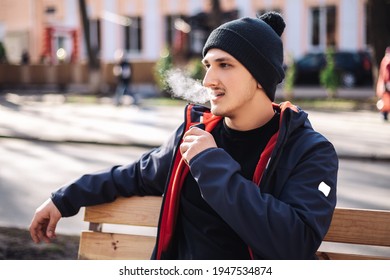 Hombre adulto joven afuera y calentador de cigarrillo electrónico para fumar tabaco. Sistema de humo y vapor con palos en el interior, imagen con espacio de copia. Hábito nocivo daño a la salud de los pulmones
