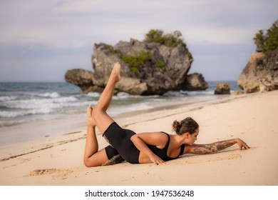 Jogja Bali. Wanita Kaukasia berlatih Salabhasana Variasi B, Pose Stag Locust di pantai. Latihan di luar ruangan. Wanita bertubuh fit. Gaya hidup sehat. Retret yoga. Pantai Thomas, Bali, Indonesia