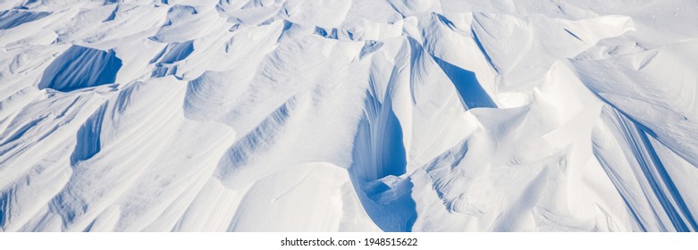 雪のテクスチャ。風が雪の表面に模様を彫ります。ツンドラや山の風が雪の表面に模様や尾根を彫ります。北極、極地。冬のパノラマ背景。
