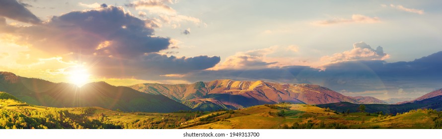 bergige ländliche Panoramalandschaft im Frühling bei Sonnenuntergang. schöne Landschaft unter einem Himmel mit Wolken im Abendlicht. grasbedeckter Hügel, der in den entfernten Kamm hineinrollt