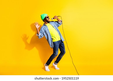 Volledige foto van charmante funky jonge donkere huid man zingen lied gelukkig geïsoleerd op gele kleur achtergrond