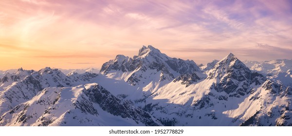 Aerial View from Airplane of Blue Snow Covered Canadian Mountain Landscape in Winter. Colorful Pink Sky Art Render. Tantalus Range near Squamish, North of Vancouver, British Columbia, Canada.