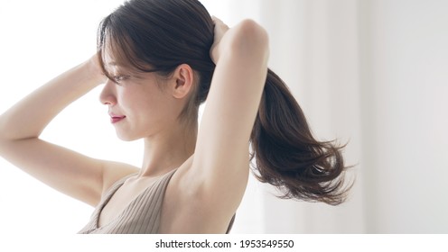 Mujer asiática joven que ata su pelo. Cuidado del cabello. Concepto de belleza.