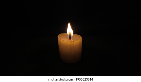 Lilin lilin terbakar putih terpencil atau batang lilin dengan nyalaan tiupan angin memberikan cahaya dalam bilik gelap yang dipenuhi dengan kegelapan malam yang pekat. Pemandangan sisi dekat mendatar yang cantik.