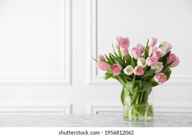 Beautiful bouquet of tulips in glass vase on white marble table. Space for text