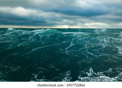 Schwerer Sturm im Ozean. Große Wellen auf offener See, bewölkter Himmel während eines Sturms und ein Frachtschiff am Horizont.