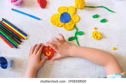 カラフルな粘土生地、粘土、粘土を使った家庭教育ゲームから花や太陽などを作る少女の手。初期の開発コンセプト。子供たちとの教育的で楽しいクラス