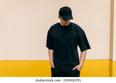 黒い空白の t シャツと黒い野球帽を身に着けている男性で、ロゴやデザイン用のスペースがあります。モックアップ