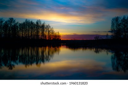 Sonnenuntergang am Ufer des Sees. Naturlandschaft. Natur in Nordeuropa. Reflexion, blauer Himmel und gelbes Sonnenlicht. Landschaft bei Sonnenuntergang.