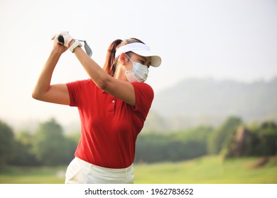 girl with mask on face for protect  corona virus and she is playing  golf on course. Golfer with golf club taking a shot