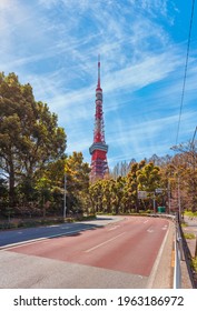 Wegkromme van de hakusan iwaida tamachi-straat omzoomd door bomen en leidt naar de Tokyo Tower, de hoogste roostertoren in Japan, geïnspireerd door de Eiffeltoren tegen een blauwe lucht met cirruswolken.