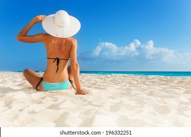 Chica joven bronceada que se sienta en la playa