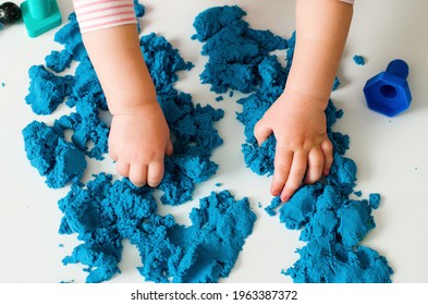Little hands playing with kinetic sand. Educational games with kids for fine motor skills. Sand therapy indoors. Concept of sensory and creativity game, therapy hand, development of fine motor, autism