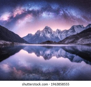 Vía Láctea sobre montañas nevadas y lago por la noche. Paisaje con rocas altas cubiertas de nieve, cielo estrellado púrpura, reflejo en el agua en Nepal. Cielo con estrellas. Increíble vía láctea brillante en el Himalaya. Espacio