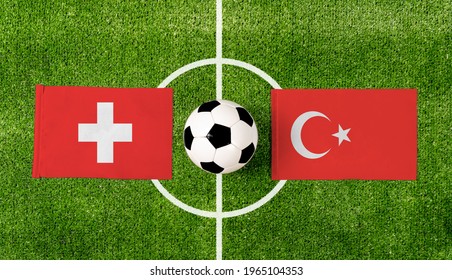Bovenaanzicht bal met Zwitserland vs. Turkije vlaggen match op groen voetbalveld.