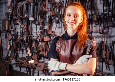 redhaired ginger young european feminist woman wearing leather apron working blacksmith workshop.small business strong and independent concept