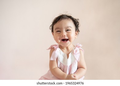 Portræt af en sød glad lille asiatisk babypige, der for nylig fik mælketand til at grine og kigge på kamera isoleret på baggrund, babyudtrykskoncept