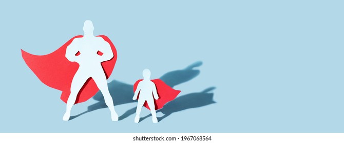 Figura de padre e hijo cortada en papel con capas de superhéroe sobre fondo azul con sombras, concepto del día del padre, pancarta, primer plano.