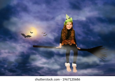 Funny 6-7 year old girl in a witch costume is flying on a broomstick on Halloween night. Fabulous fantasy photo. Happy Halloween