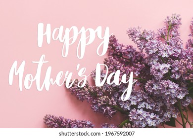 Gelukkige Moederdag. Happy mother's day tekst en lila bloemen op roze papier. Stijlvolle bloemenwenskaart. Handgeschreven letters op paarse lila tak op roze. Moederdag