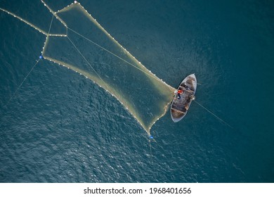 サンゴの海でヴィンテージの木製ボート。ボートのドローン写真。漁船に乗った漁師が魚を捕るために網を投げています。