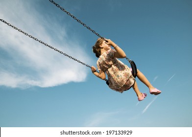 A woman on a swing and a blue sky with some cloud.
