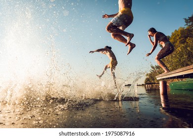 Freunde, die Spaß haben, einen Sommertag beim Schwimmen und Springen am See zu genießen.