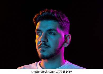 Serious, calm. Latino young man's portrait on black studio background in neon light. Handsome male model. Concept of human emotions, facial expression, youth, sales. Copy space for ad.