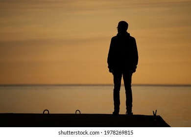 man standing on rock looking straight. Nature and beauty concept. Orange sundown. silhouette at sunset