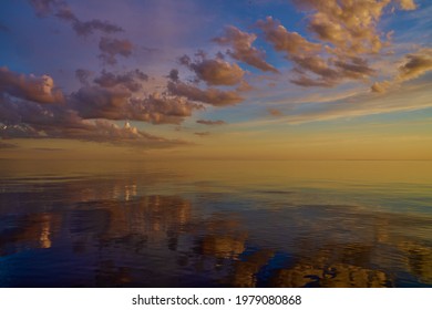 Hermosa puesta de sol sobre el mar con reflejo en el agua, majestuosas nubes en el cielo.