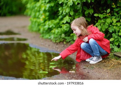 Gadis manis bermain di genangan air pada hari hujan musim panas
