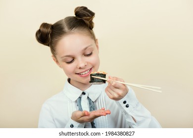 Cute smiling little girl with with sushi on light background. Student child girl eating sushi and rolls - commercial concept.