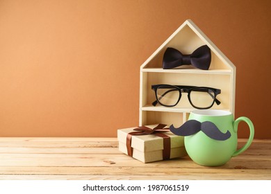 Concepto del día del padre feliz con taza de café verde, casa de juguetes y caja de regalo en la mesa de madera