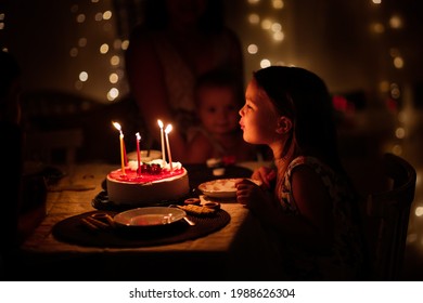 verjaardagstaart op de geboortedag van kinderen, kindmeisje blaast de kaarsjes op de taart uit, soft focus en donkere stijl, levensstijl