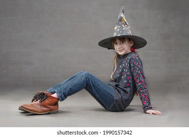 Little girl in jeans witch hat and funny boots. Child at the halloween party.