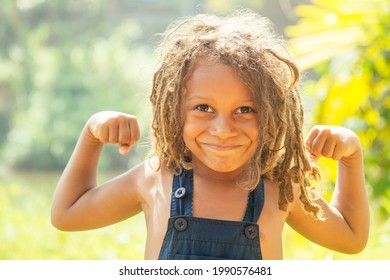 Mowgli indijski dječak s dreadlocks kosom na kojoj se vide mišićave ruke u pozadini zelene tropske šume
