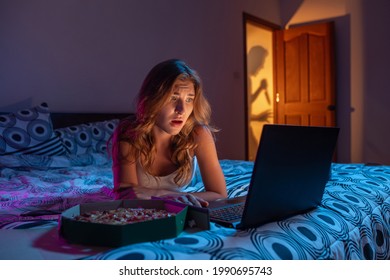 집에서 혼자 노트북으로 공포 영화를 보는 여성. 멀리서 칼을 든 살인범의 그림자