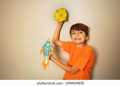 Smiling boy with rocket and planet made of paper