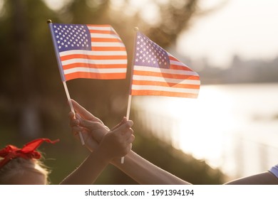 Liburan patriotik. Keluarga bahagia, ibu dan anak dengan bendera Amerika di luar ruangan saat matahari terbenam. Amerika Serikat merayakan hari kemerdekaan 4 Juli.