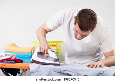 A man concentrated on ironing a shirt