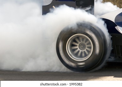 フォーミュラ 1 レーシング カーの燃え尽きと、回転するタイヤからの煙。