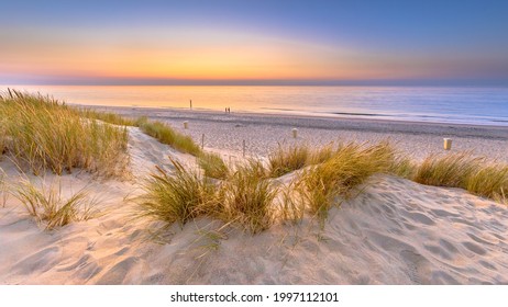 オランダのゼーラント州アウドドルプにある北海と運河の砂丘から海に沈む夕日。ヨーロッパの自然の中の海岸の屋外シーン。