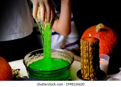 children play with a green witchcraft potion, table is covered with a black cloth, pumpkins lie, animal skulls, candles are burning, the concept of the Halloween holiday, love spell, children's party