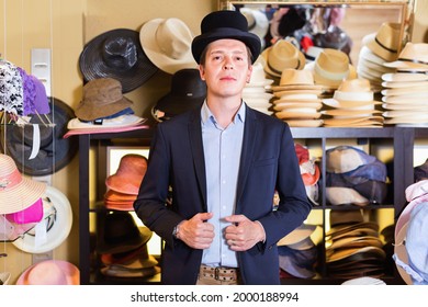 Hombre adulto alegre comprando en botique y probándose el sombrero de copa