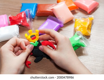 子供の手の中には空気粘土のスーパー ヒーローがあり、テーブル、クラフト、創造性、細かい運動能力、トップ ビューに色付きの粘土がたくさんあります。