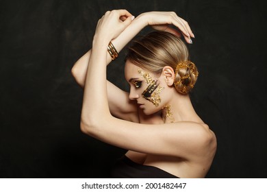 Mujer modelo morena perfecta con maquillaje dorado creativo y peinado updo con cadena de oro sobre fondo negro