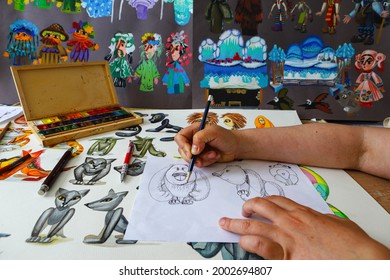 Der Animator zeichnet mit einem Bleistift und zeichnet Figuren aus Zeichentrickfilmen, Comics oder Puppenspielen. Vorbereitung zur Herstellung einer Puppe. Der Designer erstellt Skizzen. Comics, Cartoons, Puppentheater