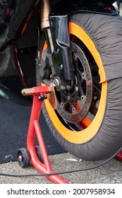 レーシング バイクの前輪のクローズ アップの詳細。ブレーキキャリパー、ローター、リム、タイヤ、サスペンションです。